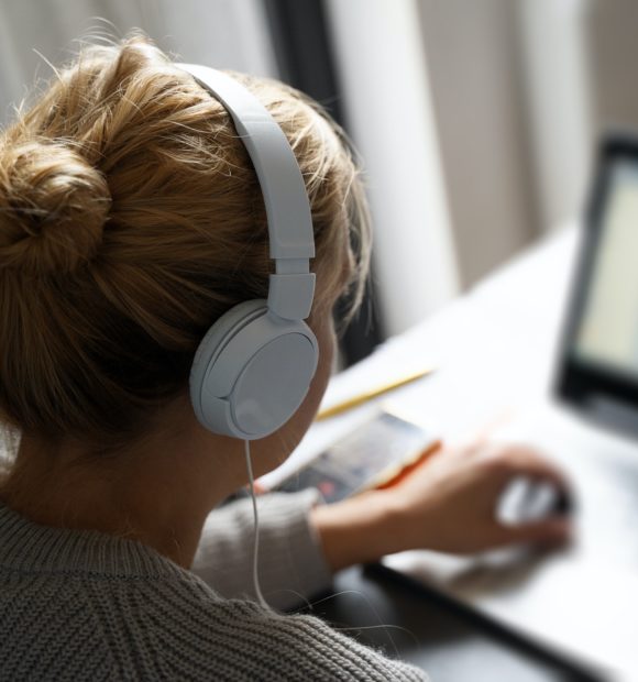 blonde woman with headphones working on notebook computer