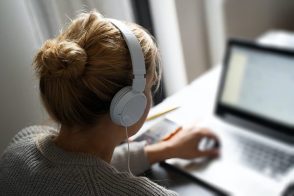 blonde woman with headphones working on notebook computer